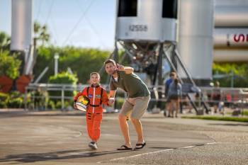 boy in astronaut suit with father in rocket garden at Kennedy Space Center