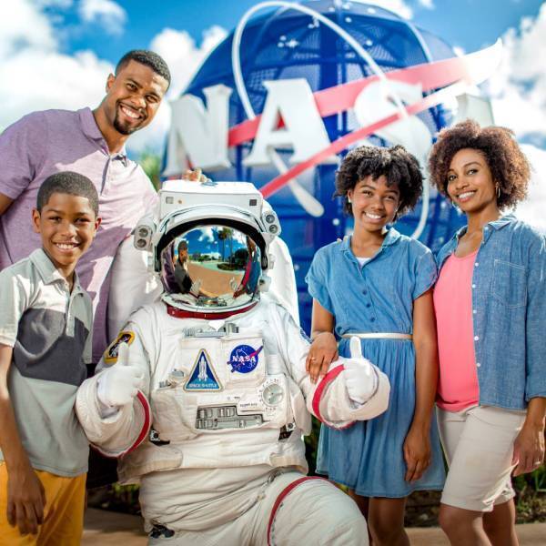 Family with astronaut in front of NASA Meatball at Kennedy Space Center